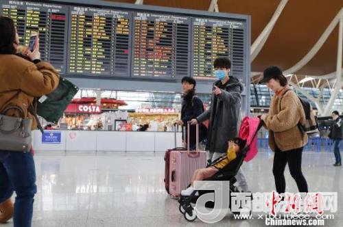 旅客帶著孩子前往辦票柜臺辦理登機手續(xù)?！∫罅⑶?攝