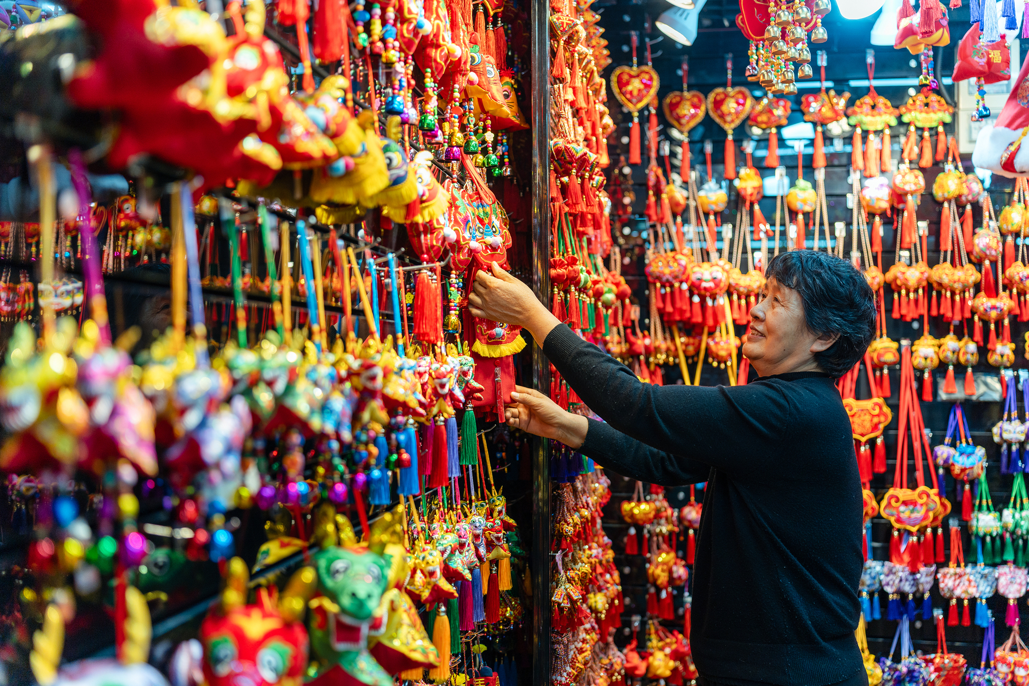 2023年12月11日，金華義烏國際商貿(mào)城，龍年喜慶用品掛滿攤位，顧客正在挑選中。