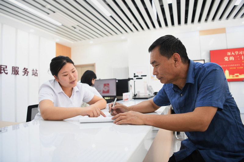 2023年5月23日，河北雄安新區(qū)容東片區(qū)南文營(yíng)社區(qū)居民（右）在社區(qū)便民服務(wù)站辦理業(yè)務(wù)。